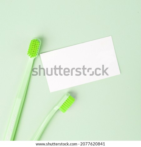 Toothbrush and business card on green background. Top view. Flat lay.