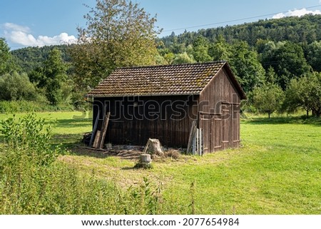 Wooden garden shed in the middle of a green meadow Royalty-Free Stock Photo #2077654984