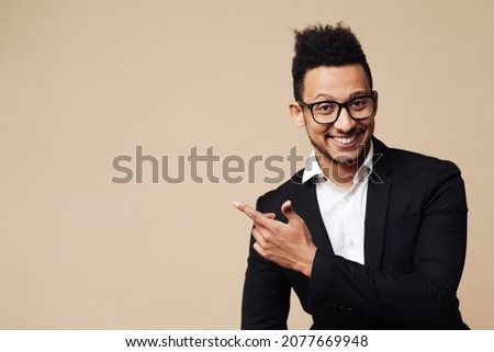 Portrait of handsome young smiling Afro man wearing glasses smiling and standing with open hand gesture isolated on beige background with copy space