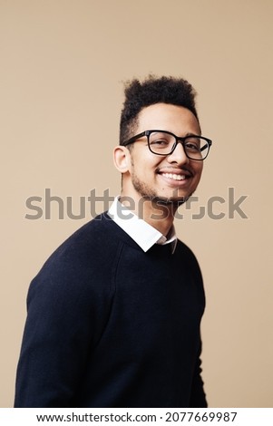 Young handsome man wearing sweater, white shirt and glasses over beige background face smiling looking at the camera. Positive person, professor style