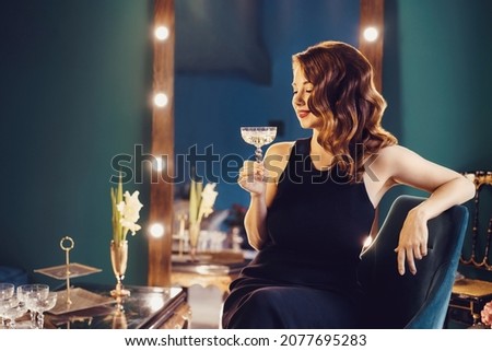 Posh elegant woman in evening dress with a glass of champagne in the luxury dressing room interior. Celebrity, superstar lifestyle. Party, drinks, holidays and celebration concept. Selective focus. Royalty-Free Stock Photo #2077695283