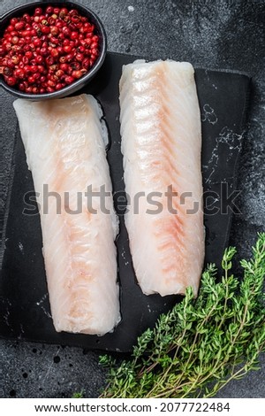 Raw cod loin fillet fish on marble board. Black background. Top view