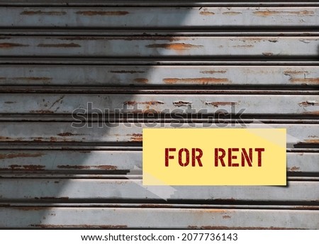 Old grunge metal door with text on note written FOR RENT, concept of a property owner or  landlord want to giving a house on rent, to boost passive income or to make regular earning from asset