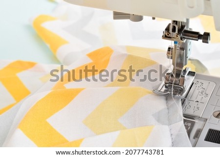 Modern sewing machine and yellow fabric in zigzag. Sewing and home needlework. Flat layout, copy space, close-up, banner, layout