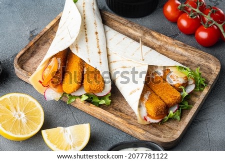 Sandwich roll with fish fingers, cheese and vegetables set, on wooden tray, on gray background
