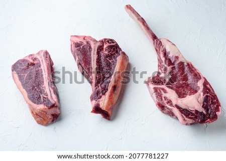 Dry aged raw beef meat set, tomahawk, t bone or porterhouse and club steak, on white stone  background Royalty-Free Stock Photo #2077781227