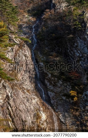 View of waterfall on the cliff in the autumnal mountain