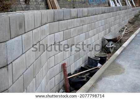 ugly holding a road notch of a bridge forecourt tunnel. retaining wall with concrete grouting is covered with fake, optically prettier wall. fencing with hollow bricks filled with wires, railing,steel Royalty-Free Stock Photo #2077798714
