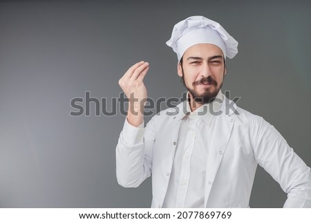 Amazed young male Italian handsome chef. He is Gesturing delicious sign, studio shot includes copy space.