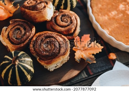 Thanksgiving festive table. Autumn style table setting with pumpkins, leaves and physalis. Pumpkin pie and cinnamon rolls. Cozy autumn scene. Flat lay. Fall styled composition.