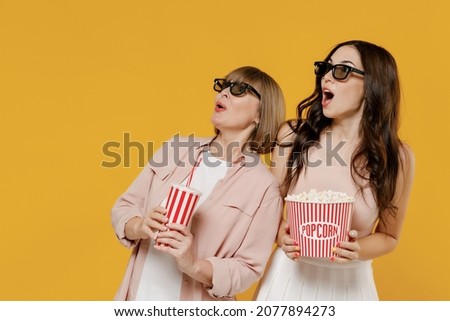 Two young amazed daughter mother woman in 3d glasses watch movie film hold bucket of popcorn cup of soda pop isolated on yellow background studio portrait People emotions in cinema lifestyle concept Royalty-Free Stock Photo #2077894273