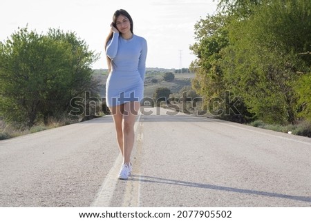 A young Hispanic female posing on the empty road