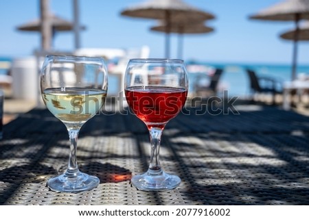 Drinking of cold rose and white wines in lounge bar on sunny sandy beach with blue sea water on background, summer vacation