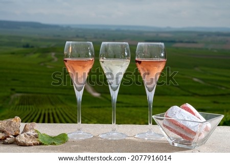 Glasses of white and rose brut champagne wine, firestones from vineyard soil and view on grand cru vineyards of Montagne de Reims near Verzenay, Champagne, France