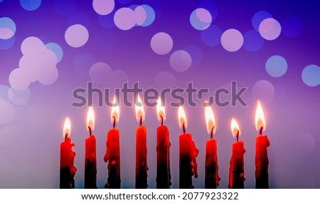 Burning festive candles are traditional symbols of Hanukkah Holiday of Light, selective focus on menorah with wax candles, blurred background with festive bokeh