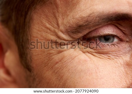 Close-up of wrinkles near the eyes of a mature man. Royalty-Free Stock Photo #2077924090