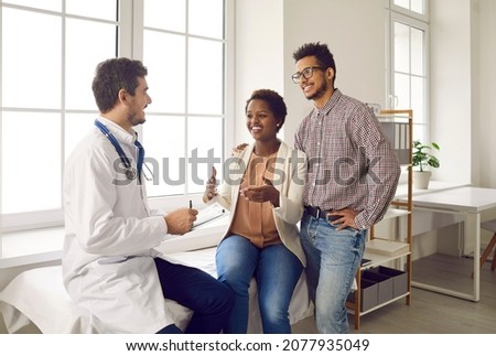Happy ethnic couple getting professional help from their doctor. Young family planning pregnancy and visiting general practitioner, gynecologist, OB GYN obstetrician or IVF expert for health check up Royalty-Free Stock Photo #2077935049