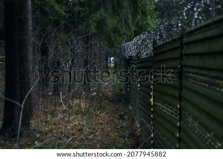 Tall fence with barbed wire angle shot outdoors autumn leafs