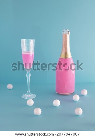 Pink champagne bottle and tall Art Deco glass. Minimal party layout against pastel blue background. Celebration, Happy New Year toast.