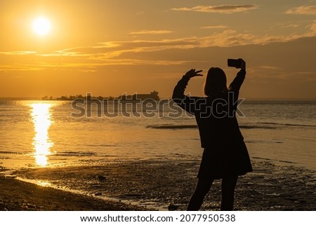 a young girl at sunset takes a selfie. happy man on the beach in the evening. advertising picture. space for printing.