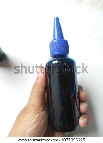 holding blue refill ink on bottle on white background for printing needs