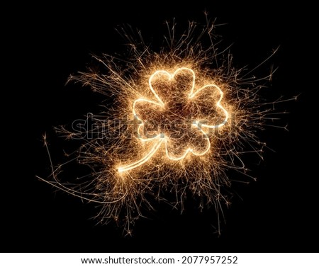 golden bright sparkler four leaf clover shape happiness shaped symbol isolated on dark black background. silvester new year birthday wedding and celebration design pattern