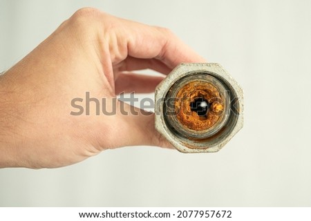 Old calcified and clogged water pipe with brown rust held in hand by plumber Royalty-Free Stock Photo #2077957672