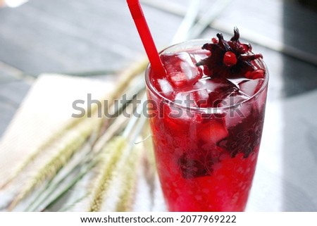 roselle juice in a glass, placed on a white table.