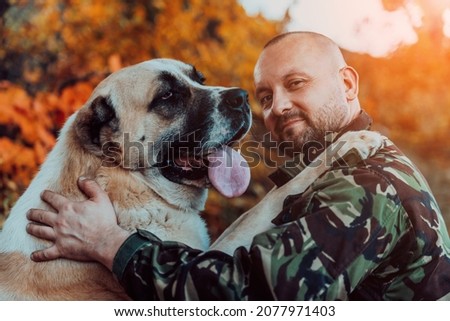 Handsome man playing with a big dog in the autumn forest. Selective focus