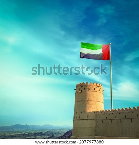 Flag of UAE flying on the fort against blue sky background. National Day marks the UAE's formal nationalisation in 1971.