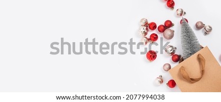 Christmas tree in a craft gift bag, decorative balls on a white background. Top view, flat lay. Banner