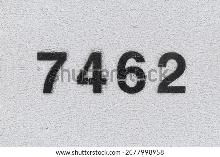 Black Number 7462 on the white wall. Spray paint. Number seven thousand four hundred and sixty two.