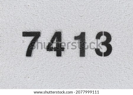Black Number 7413 on the white wall. Spray paint. Number seven thousand four hundred thirteen.