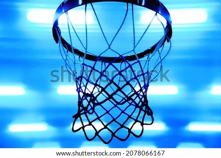 Basketball hoop against background of bright spotlights on ceiling. Bottom view. Sporty back. Blue Neon color.