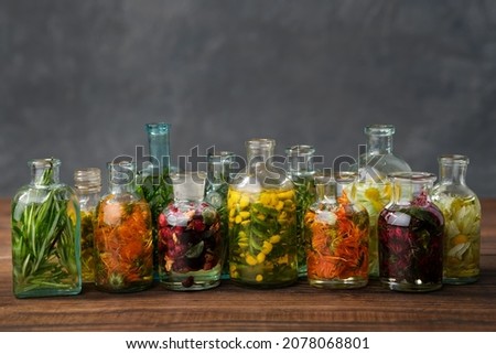 Bottles of essential oil or infusion of medicinal herbs and berries - rosemary, calendula, tansy, thuja, thyme, bergamot, chamomile.  Healing plants, medicinal herbs and berries. Alternative medicine. Royalty-Free Stock Photo #2078068801