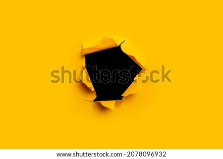 Bright yellow torn paper inside a black hole in a hole Royalty-Free Stock Photo #2078096932