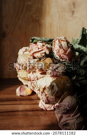A bouquet of aged, withered and withered yellow pink roses. The lights of a sun