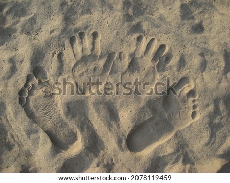 Footprints and handprints on the sand.