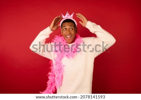 A dark-skinned young ma in a crown and with a pink garland