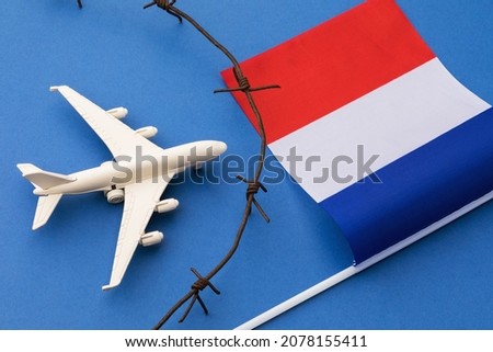 French flag, barbed wire and toy plane on blue background, concept on France air border violation Royalty-Free Stock Photo #2078155411