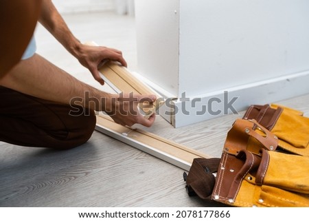 Mans hands putting white baseboard. Royalty-Free Stock Photo #2078177866