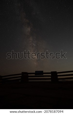 A silhouette of a fence and a milky way in a night starry sky