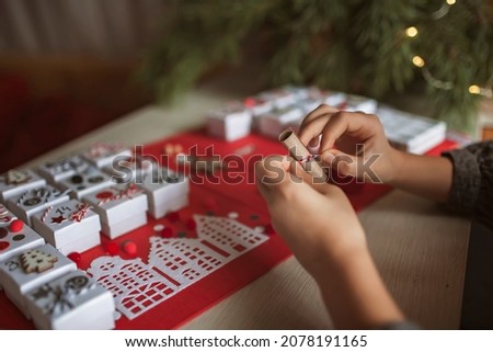 Pretty girl holds an original advent calendar made of jewelry boxes and a binder, New Year craft, diy. Magic of moment, seasonal activity. Christmas miracle. Soft focus, depth of field