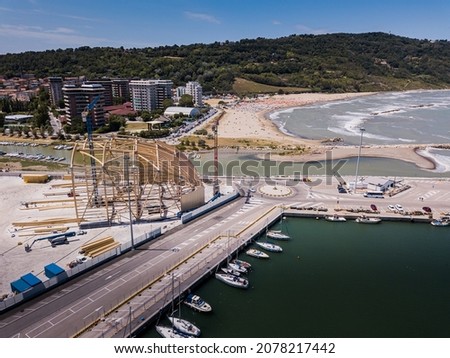 An aerial shot over a beautiful port with many boats and ships, buildings and green mountain