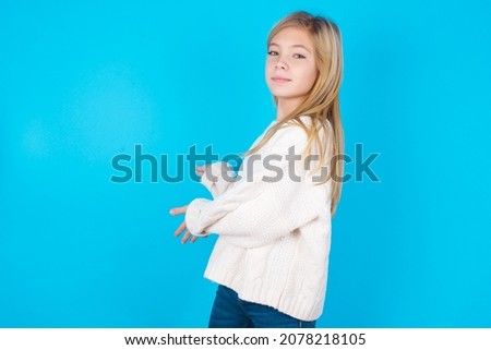 caucasian little kid girl wearing white knitted sweater over blue background Inviting to enter smiling natural with open hands. Welcome sign.