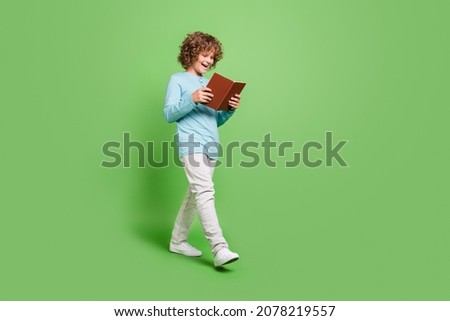 Full length body size view of attractive cheerful amazed guy reading book going isolated over vivid green color background