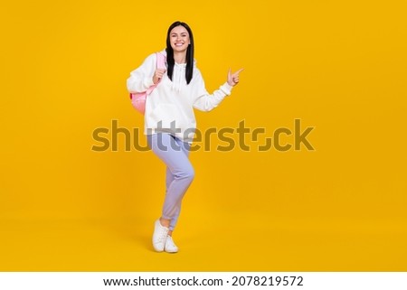Full length photo of lady hold backpack indicate hand empty space 1-september adverts isolated over bright yellow color background