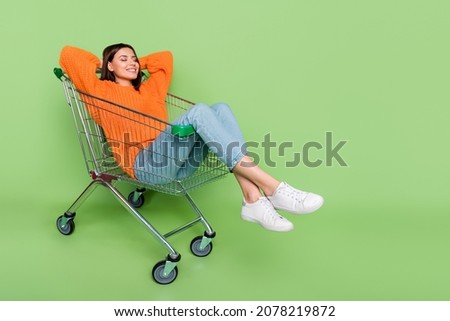 Portrait of attractive dreamy cheerful girl riding cart lying resting silence isolated over bright green color background Royalty-Free Stock Photo #2078219872