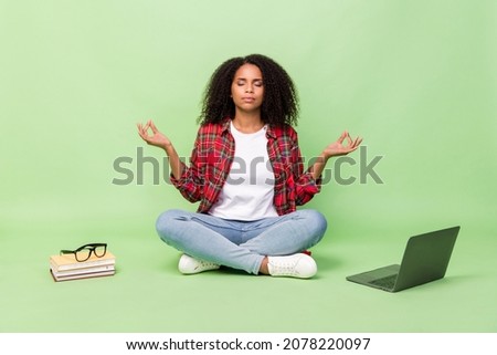 Full size photo of young attractive african lady sit lotus pose meditate dream break laptop isolated over green color background