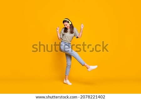 Full size photo of young pretty attractive smiling cheerful positive girl in headphones dancing isolated on yellow color background